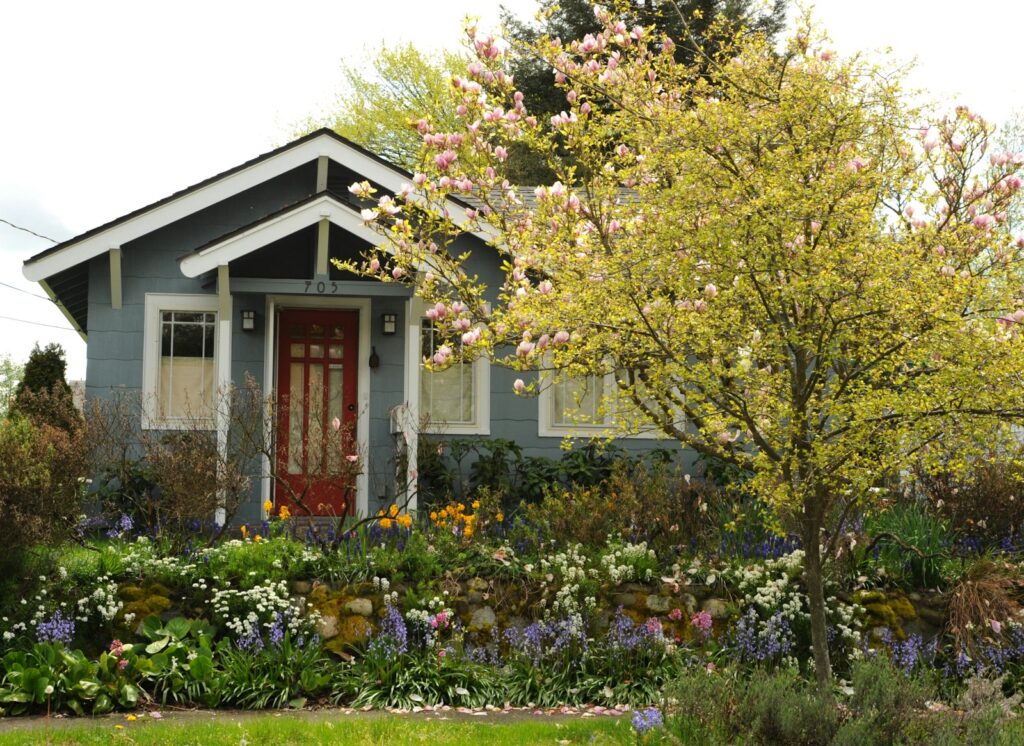 white and brown house surrounded by green trees and plants